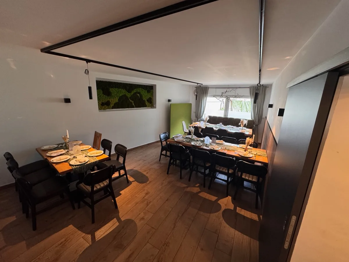 Länglicher Raum mit festlich gedeckter langer Tafel und dunklen Stühlen, rechts ein Fenster.
