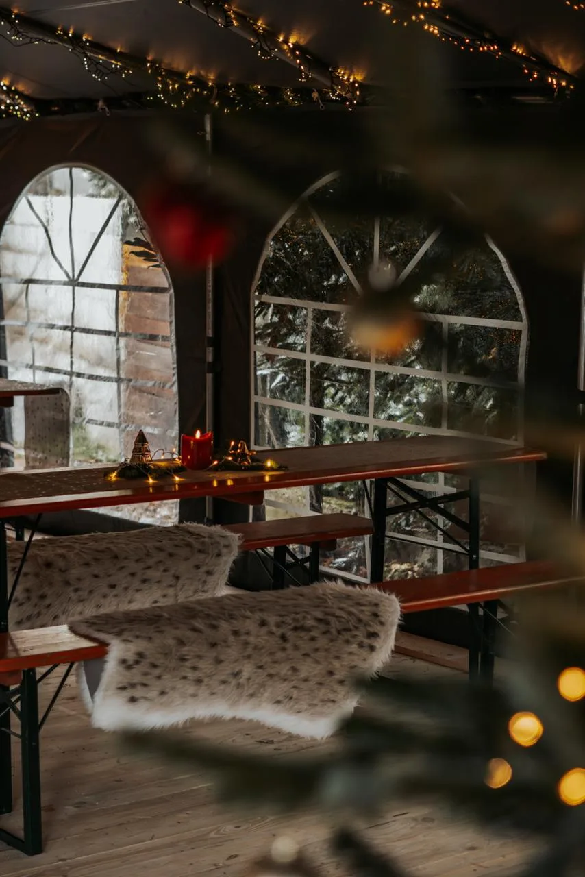 Zelt mit Bierzeltgarnituren und Schaffellen, Rundbogenfenster und Weihnachtsschmuck.
