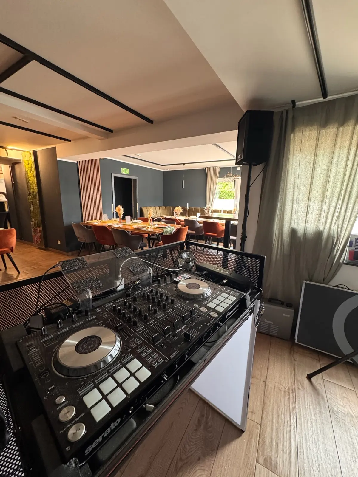 DJ-Pult mit Controller im Gastraum, dahinter gedeckte Tische.
